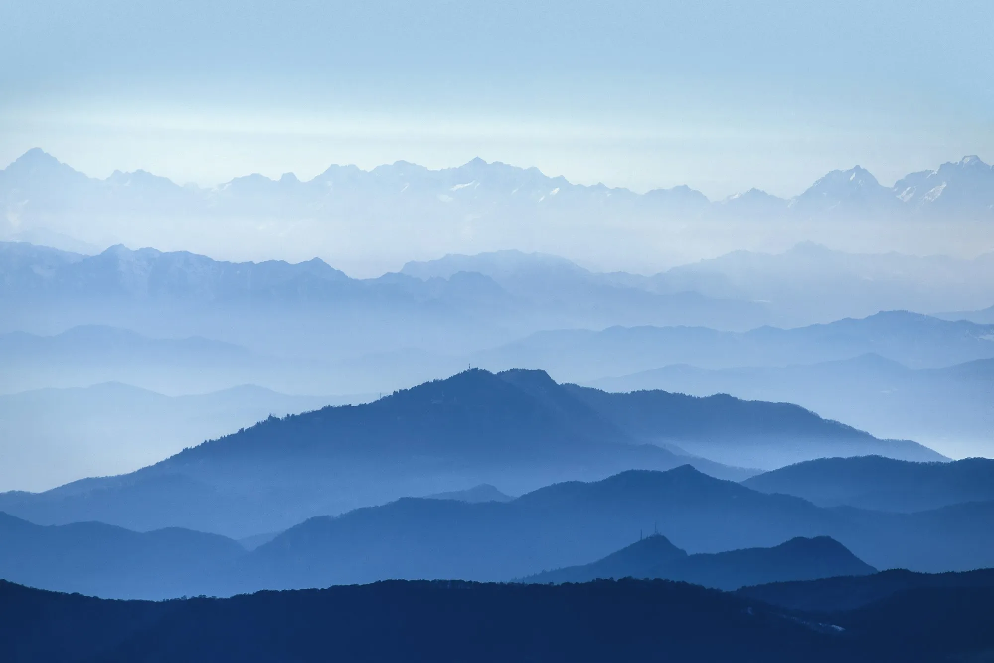 Layered blue mountain ridges fading into haze as the Mac desktop wallpaper, with Snippet's notch panel open at the top